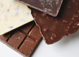 A stack of delectable dark, milk, and white chocolate bars on a white surface.